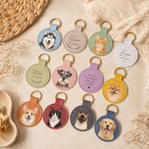 May include: A collection of twelve circular leather keychains in various colors, each featuring a gold-tone metal ring. Some keychains display custom pet portraits, while others are personalized with names, dates, and memorial text in black ink.