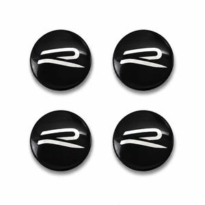 May include: Four circular black emblems with a glossy finish, each featuring a stylised white letter R graphic centred on the surface. The design consists of a smooth, rounded shape with a clean, high-contrast appearance for each individual piece.