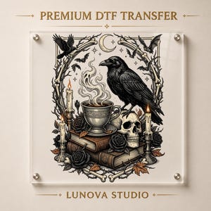 May include: A clear acrylic sign featuring a graphic print labeled PREMIUM DTF TRANSFER and LUNOVA STUDIO. The illustration depicts a black raven perched on a human skull, a steaming teacup on stacked books, lit candles, roses, and bats.