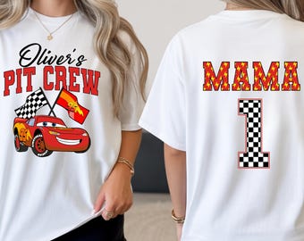 Może przedstawiać: Biała koszulka z grafiką czerwonego samochodu wyścigowego, napisem 'Oliver's PIT CREW' i dwiema flagami w szachownicę z przodu oraz słowem 'MAMA' nad dużą cyfrą '1' z wzorem w szachownicę na plecach ubrania.