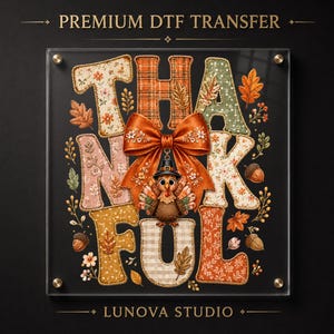 May include: A Premium DTF Transfer sheet from Lunova Studio featuring the word THANKFUL in large, patterned letters. The design includes a central orange bow, a cartoon turkey wearing a pilgrim hat, and various autumn leaves and acorns.