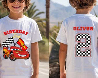 Może przedstawiać: Biały t-shirt z grafiką czerwonego samochodu wyścigowego, napisem "BIRTHDAY Boy" z przodu oraz imieniem "OLIVER" nad dużą szachownicową cyfrą "2" z tyłu. Wzór zawiera flagę w szachownicę oraz czerwoną flagę z symbolem błyskawicy.