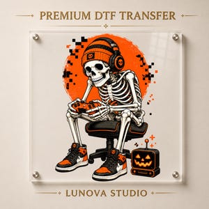 May include: A graphic print labeled PREMIUM DTF TRANSFER and LUNOVA STUDIO featuring a skeleton wearing an orange beanie and headphones, sitting on a chair while playing a video game. A small jack-o'-lantern television sits on the floor nearby.