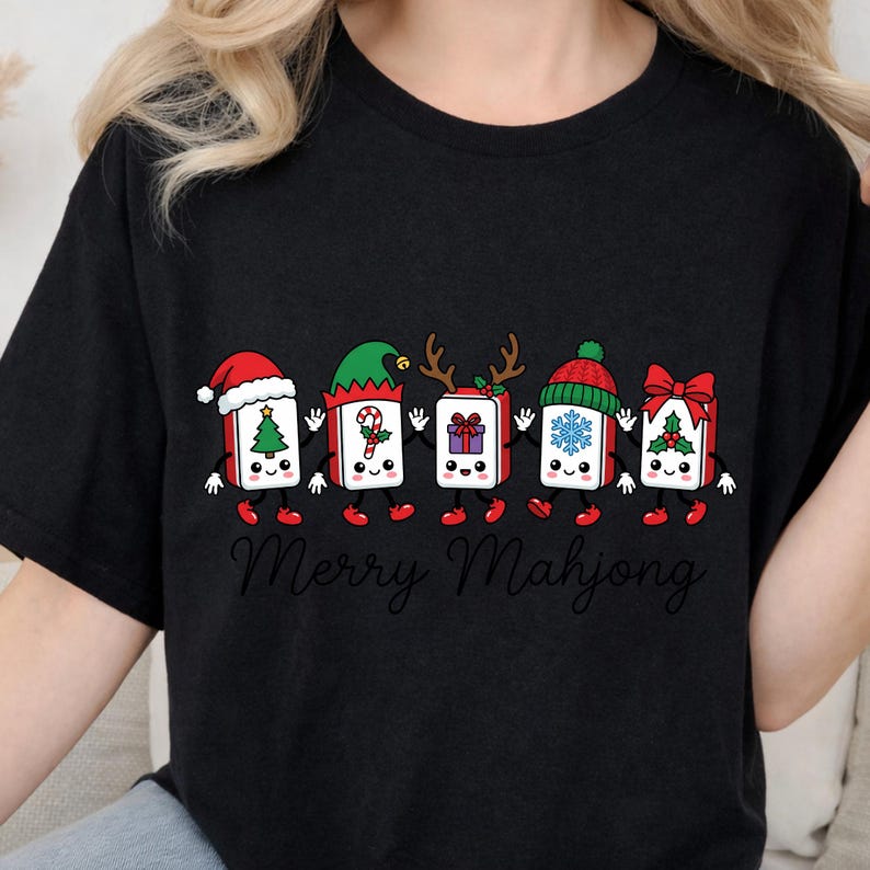 Może przedstawiać: Czarny t-shirt z grafiką przedstawiającą pięć antropomorficznych płytek mahjonga trzymających się za ręce. Każda płytka ma inny świąteczny dodatek, w tym czapkę Mikołaja, czapkę elfa, rogi renifera, dzianinową czapkę i czerwoną kokardę.