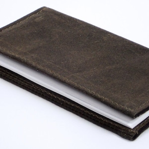 May include: A brown leather-bound journal with a stitched edge and a white paper interior.