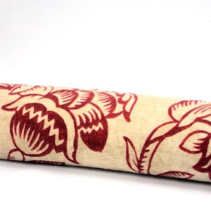 May include: A beige fabric with a red floral pattern. The fabric has a soft, velvety texture and features a repeating design of stylised flowers.