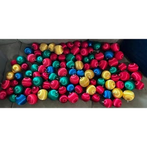 May include: A large collection of spherical ornaments in a variety of vibrant colors including red, green, blue, and yellow. Each ornament features a smooth, satin-like finish and a small silver-toned cap at the top for hanging purposes.
