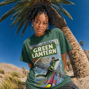 Pode incluir: Uma t-shirt de manga curta verde-escura com um gráfico de capa de banda desenhada vintage do Green Lantern. A impressão mostra o título Green Lantern, a personagem a voar sobre uma ponte e um foguetão vermelho com chamas amarelas.