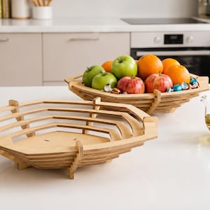 May include: Two hexagonal fruit bowls constructed from light-colored plywood with a 3 mm material width. The bowls feature a layered, laser-cut design with open sides. One bowl is empty, while the other contains a variety of fresh fruit.