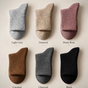 May include: Six pairs of 98% Merino Wool socks in light grey, oatmeal, dusty rose, caramel, charcoal, and black. The text reads 98% Merino Wool Socks, Soft, Warm, Breathable, and Natural Comfort for Everyday. Each sock features a ribbed cuff.