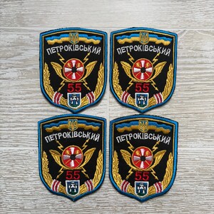 Könnte beinhalten: Vier identische gestickte Aufnäher in schwarzer Schildform mit blauem Rand. Das Design zeigt ein zentrales rot-weißes kreisförmiges Emblem, goldene Blitze, Weizenähren, die Zahl 55 in Rot und den kyrillischen Schriftzug PETROKIVSKYI.