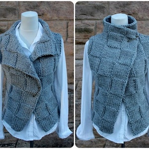 May include: A gray knitted vest with a high collar and a unique asymmetrical design. The vest has a button closure and a textured pattern.
