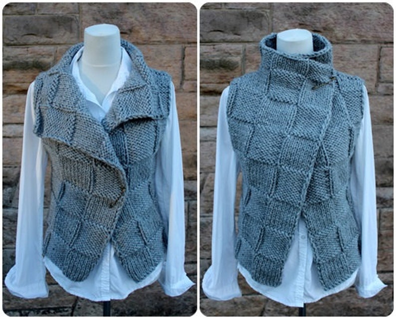 May include: A gray knitted vest with a high collar and a unique asymmetrical design. The vest has a button closure and a textured pattern.