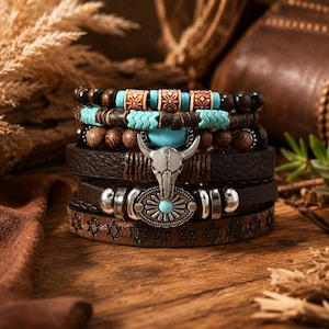 May include: A multi-layered bracelet set featuring dark brown leather straps, wooden beads, and turquoise-coloured accents. The centrepiece is a silver-toned bull skull charm and a circular metal emblem with a central turquoise stone and star patterns.
