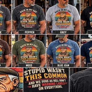 Könnte beinhalten: Ein kurzärmeliges T-Shirt in verschiedenen Farben mit einer Grafik einer älteren Person mit Schiebermütze und verschränkten Armen. Der Text lautet: BACK IN MY DAY STUPID WASN'T THIS COMMON AND WE SURE AS HELL DIDN'T HAVE WARNING LABELS ON EVERYTHING.