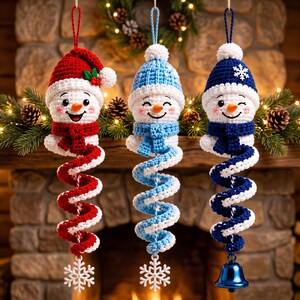 May include: Three crocheted snowman ornaments hanging vertically. The left snowman wears a red hat with holly, the center a light blue hat, and the right a dark blue hat with a snowflake. Each has a spiral body and a white snowflake or bell.