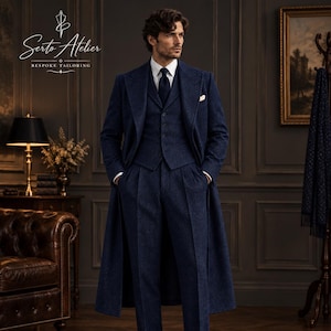 May include: A dark blue three-piece suit featuring a long overcoat, a buttoned waistcoat, and pleated trousers, worn with a white collared shirt and a dark tie. The Serto Atelier Bespoke Tailoring logo is visible in the upper left corner of the image.