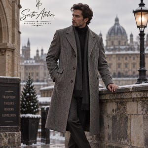 May include: A long, grey herringbone wool overcoat worn over a dark turtleneck sweater and dark trousers, paired with a matching grey scarf with fringe ends and dark brown leather dress shoes, featuring the Serto Atelier Bespoke Tailoring logo.