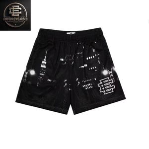 May include: Black athletic mesh shorts featuring a white graphic print of a city skyline and a prominent white logo on the lower right leg. The shorts have an elastic waistband and a small white tag centered at the top of the waistband.