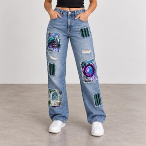 May include: Light blue denim jeans featuring a high-waisted fit, belt loops, and a button-fly closure. The jeans are decorated with various rectangular patches, including dark green and black striped fabric and graphic prints of gothic scenes.