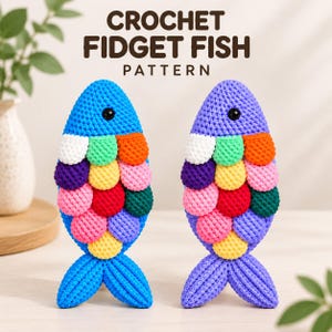 Könnte beinhalten: Zwei gehäkelte Fische mit dem Text CROCHET FIDGET FISH PATTERN darüber. Der linke Fisch ist blau mit bunten Schuppen in Weiß, Grün, Orange, Lila, Gelb, Pink, Rot und Dunkelgrün. Der rechte Fisch ist lila und hat ein ähnliches Schuppenmuster.