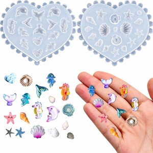May include: Two heart-shaped silicone molds with various sea-themed cavities, including dolphins, seahorses, jellyfish, seashells, and starfish. The set includes multiple colorful, finished resin charms shaped like these marine creatures and shells.