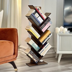 May include: A dark brown wooden tree-shaped bookshelf with a vertical central spine and angled shelves extending from both sides. The unit is filled with various books of different sizes and colors, stacked horizontally on each of the slanted tiers.