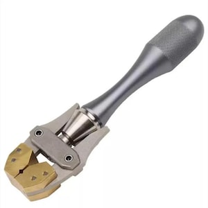May include: A metal leathercraft edge creaser tool featuring a long, cylindrical, textured silver handle and a dual-pronged brass head. The tool has a mechanical hinge mechanism connecting the handle to the brass creasing tips, designed for manual leather working tasks.
