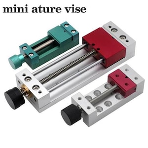May include: Three metal mini ature vise tools with adjustable screw mechanisms. One vise is green with a matching knob, while the other two feature silver bases with red sliding blocks and black adjustment knobs. The text mini ature vise is visible.