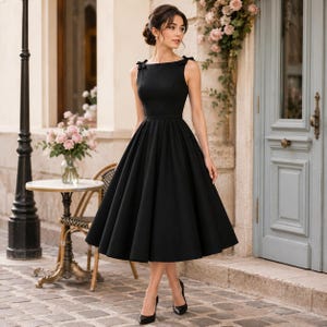 May include: A black midi dress featuring a boat neckline, sleeveless bodice with small bows on the shoulders, and a full, pleated skirt that falls below the knees. The garment is constructed with a structured waistline and a solid, matte finish.