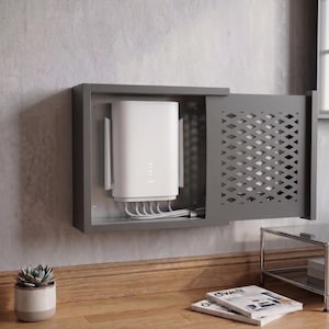 Könnte beinhalten: Ein an der Wand montiertes graues Metallgehäuse mit einer verschiebbaren Tür im Rautenmuster, das einen weißen WLAN-Router mit mehreren angeschlossenen Kabeln enthält. Die rechteckige Einheit bietet eine sichere und organisierte Aufbewahrung.