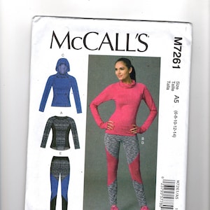 May include: McCall's sewing pattern M7261 showing athletic wear designs. The pattern includes a pink long-sleeved top and leggings with grey and pink panels. Also shown are a blue hooded jacket and a black and grey top and leggings.