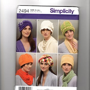 May include: Simplicity sewing pattern 2494 for hats in sizes S, M, and L. The envelope displays six variations of headwear including a purple turban, a white cloche with floral detail, a green cap with braided trim, an orange beanie, a multi-colored patterned cap, and a yellow ribbed hat.