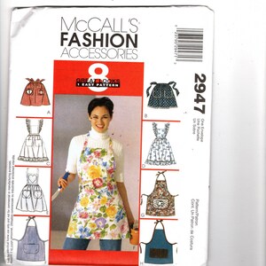 May include: A McCall's Fashion Accessories sewing pattern envelope, number 2947, featuring illustrations and a photograph of eight different apron designs. The cover displays various styles including floral, solid, and patterned aprons with pockets.