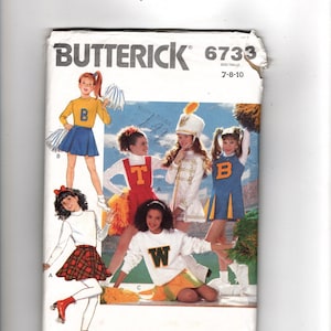 May include: A Butterick 6733 sewing pattern envelope for children's sizes 7-8-10. The cover features illustrations of children wearing various cheerleading and marching band uniforms, including skirts, sweaters, and hats, with pom-poms and roller skates.