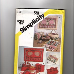 May include: A Simplicity sewing pattern envelope with a yellow border. The cover features illustrations of various fabric crafts, including bags, baskets, and a wall hanging. The text "Simplicity" is prominently displayed.