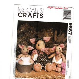 May include: McCall's Crafts sewing pattern featuring three stuffed pig dolls. The pigs have pink ears and snouts, with one in a metal tub. The pattern is titled "Straw Stockings".