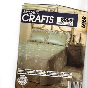 May include: A vintage McCall's Crafts pattern for bedroom essentials. The cover features a bed with a green floral patterned bedspread, matching pillows, and a nightstand. The pattern number is 8959, and the instructions are for making bedspreads, comforters, dust ruffles, and pillow shams.
