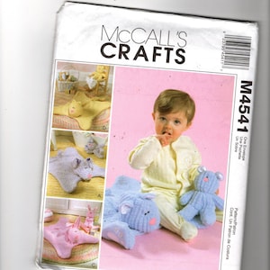 May include: McCall's Crafts pattern envelope featuring a baby with a blue stuffed animal and a blue stuffed animal shaped pillow. The envelope has images of other stuffed animal patterns. The text "M4541" is visible.