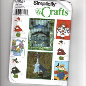 Könnte beinhalten: Simplicity Crafts-Schnittmuster mit verschiedenen Bastelprojekten zum Thema Gans. Das Muster enthält Designs für Gänse in festlichen Outfits, darunter ein Weihnachtsmann, eine Hexe und eine Vogelscheuche. Das Muster enthält auch Designs für Fische und Blumenarrangements.