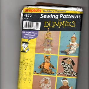 Pode incluir: Um envelope de molde de costura Simplicity 4872 para fantasias de criança pequena com ilustrações de seis trajes diferentes, incluindo um palhaço, um tigre, um dálmata e um coelho. A embalagem amarela e preta exibe o texto Sewing Patterns for Dummies.