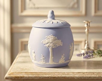 May include: A light blue ceramic jar with a matching lid featuring a finial. The exterior is decorated with white relief carvings depicting a central tree, human figures, and floral motifs in a matte finish, creating a textured appearance.