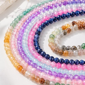 Può includere: Più fili di perline di pietre preziose sfaccettate e rotonde disposte in un motivo circolare. Le perline presentano una varietà di colori traslucidi tra cui verde, viola, rosa, azzurro, blu scuro, giallo, marrone e trasparente.