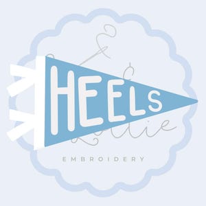 Op de afbeelding: Een lichtblauwe driehoekige wimpel met de witte tekst HEELS in een vetgedrukt schreefloos lettertype. Achter de wimpel bevindt zich een lichtblauw geschulpt cirkelvormig embleem met het woord EMBROIDERY in kleine witte hoofdletters.