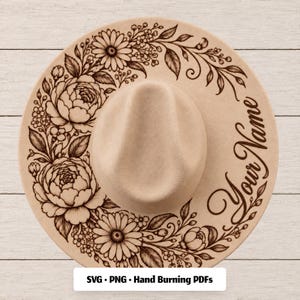 May include: A beige fedora hat featuring a dark brown laser-engraved floral pattern of daisies and peonies along the brim, with the text "Your Name" in a cursive script on the right side and "SVG • PNG • Hand Burning PDFs" at the bottom.