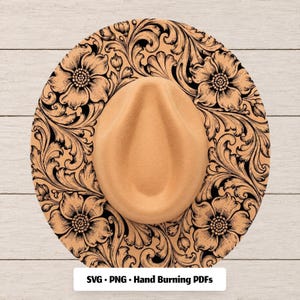 May include: A tan felt hat featuring a black floral and scrollwork pattern printed on the brim. The crown has a central indentation. A white rectangular label at the bottom displays the text: SVG • PNG • Hand Burning PDFs.