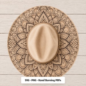 May include: A tan fedora hat featuring a detailed black mandala pattern printed on the brim. The crown is oval-shaped with a central crease. Below the hat, a white rectangular label displays the black text: SVG • PNG • Hand Burning PDFs.