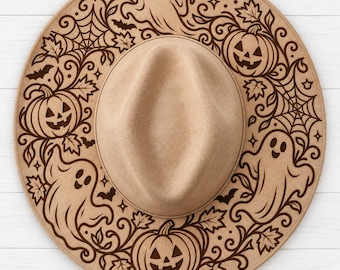 May include: A tan felt hat featuring a dark brown laser-engraved pattern on the brim. The design includes smiling ghosts, jack-o'-lanterns, spiderwebs, bats, and maple leaves arranged in a circular motif around the central crown.
