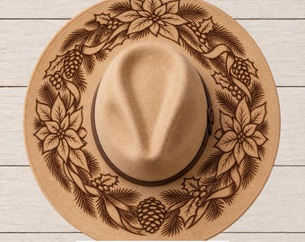May include: A tan felt fedora hat featuring a dark brown laser-engraved wreath design of poinsettias, pine needles, pinecones, and holly berries on the brim. A dark brown band encircles the crown. Text at the bottom reads: SVG • PNG • Hand Burning PDFs.