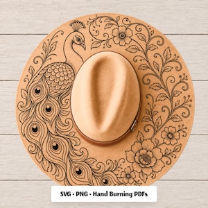 Op de afbeelding: Een beige vilten hoed met een zwart lijntekeningontwerp van een pauw met een lange staart en bloemranken. De hoed heeft een bruine leren band rond de kroon. Een wit label onderaan toont de tekst: SVG • PNG • Hand Burning PDFs.